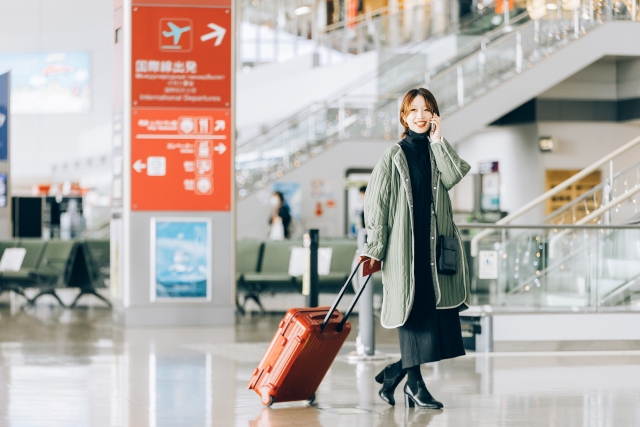 空港でスーツケースを引く女性
