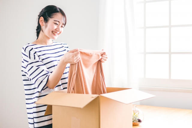 届いた箱から衣類を取り出して確かめる女性